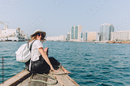 Young beautiful woman sitting at boat and looking at sea and the city DUbai