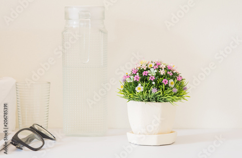 Plastic flower bouquet in a pot placed on a white wooden in a bed room