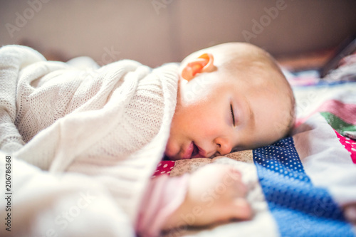 A toddler girl sleeping on a bed at home.