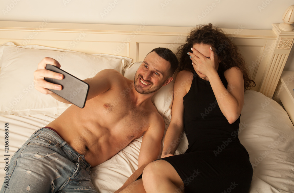 Couple taking selfie. Happy sexy couple taking photo. sexy woman in black  dress. Sexy couple in bed. man is embarrassed. Funny faces Stock Photo |  Adobe Stock