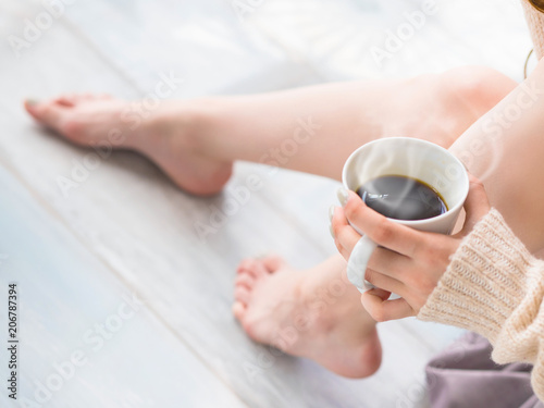 Female feet and a cup of tea or coffee. daylight.