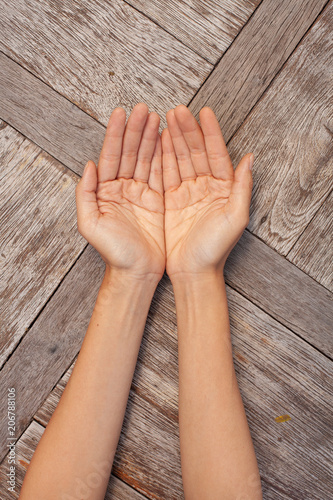Two female hands showing open palms on wooden background.