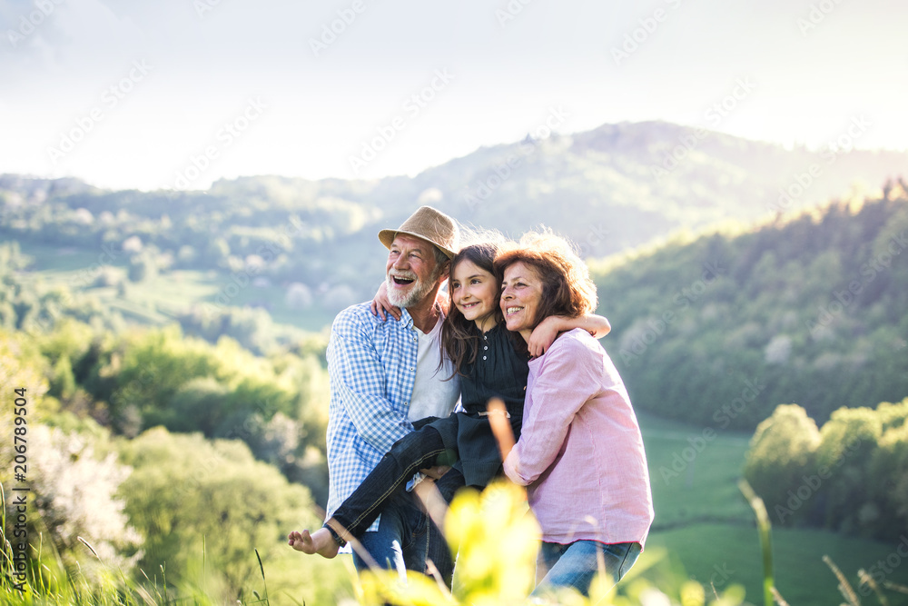 Senior couple with grandaughter outside in spring nature, relaxing and having fun.