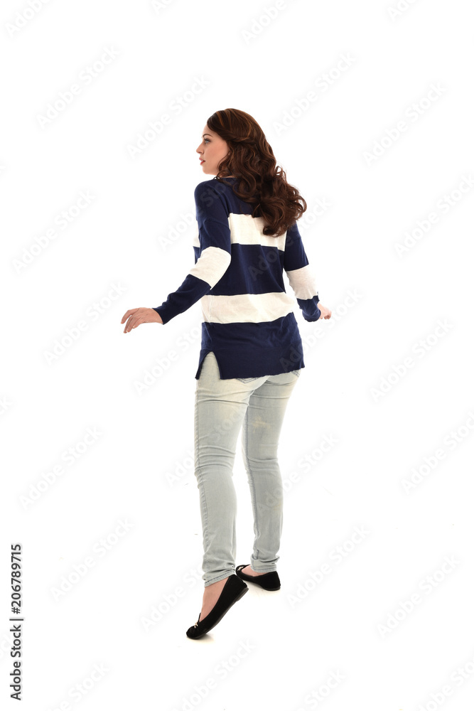 full length portrait of girl wearing striped blue and white jumper and jeans. standing pose  facing away from the camera, on white studio background