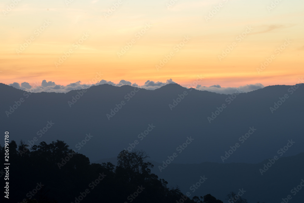 Mountain silhouette, the clouds at sunrise, warm yellow sunlight, sunset and sunrise, view from the top view of mountains.