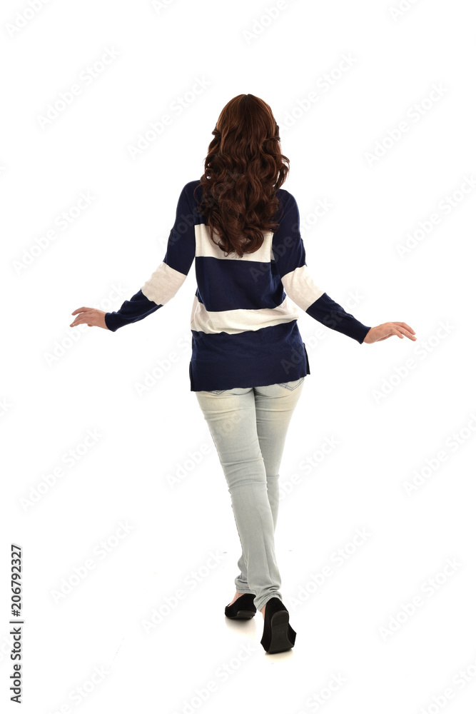 full length portrait of girl wearing striped blue and white jumper and jeans. standing pose facing away from the camera, on white studio background full length portrait of girl wearing striped blue and white jumper and jeans. standing pose facing away from the camera, on white studio background