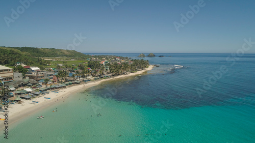 Aerial view of beautiful tropical beach with turquoise water in blue lagoon, Pagudpud, Philippines. Ocean coastline with sandy beach. Tropical landscape in Asia.