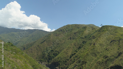 Aerial view of mountains covered forest, trees against the sky and clouds.Cordillera region. Luzon, Philippines. Mountainous tropical landscape.