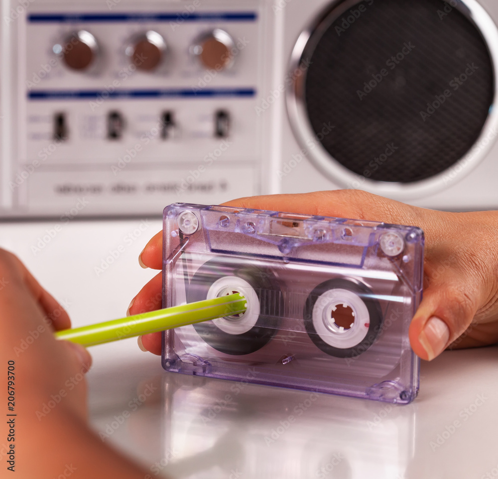 Woman reeling compact audio cassette with a pen Photos | Adobe Stock
