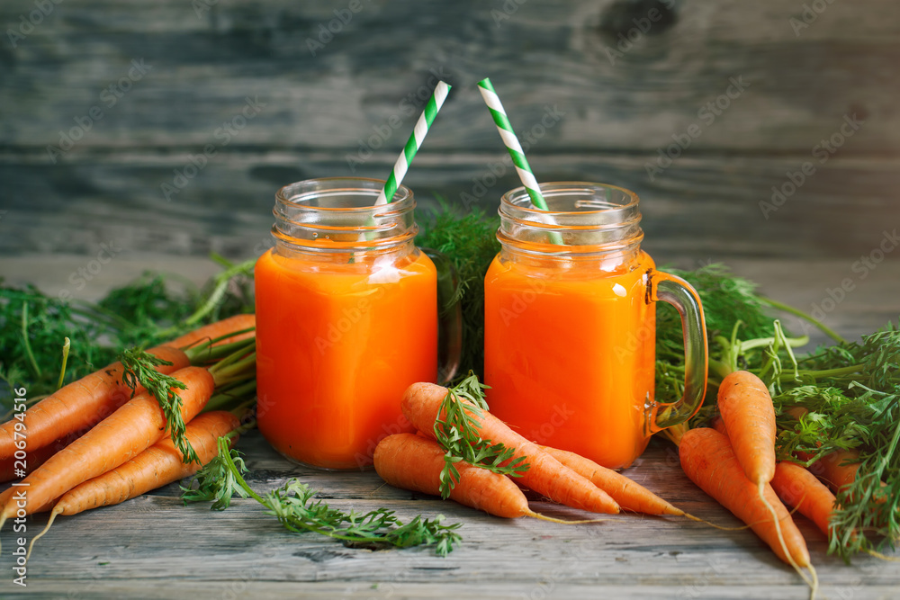 Fresh Carrot and carrot juice on Wooden Table in Garden. Vegetables Vitamins Keratin. Natural Organic Carrot lies on Wooden background. Fresh Carrot and carrot juice on Wooden Table in Garden. Vegetables Vitamins Keratin. Natural Organic Carrot lies on Wooden background.