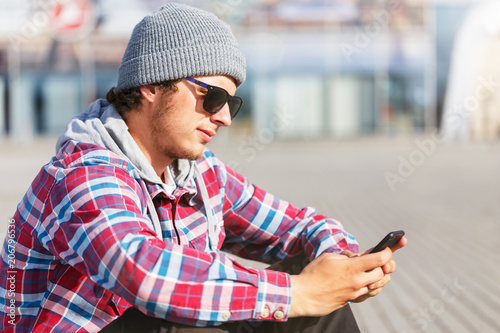 Portrait of hipster man with sunglasses holding smartphone
