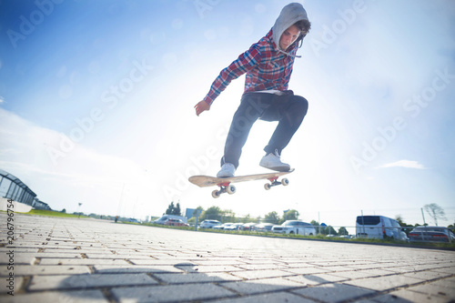 Skateboarder makes jump trick on board against sunset