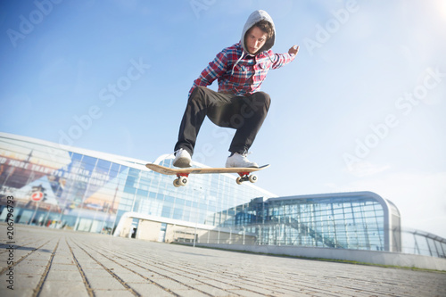 Skateboarder makes jump trick on board against sunset