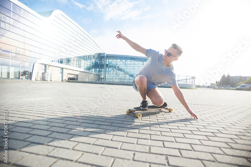 Skateboarder rides longboard on brick ground before sunset, sunny day