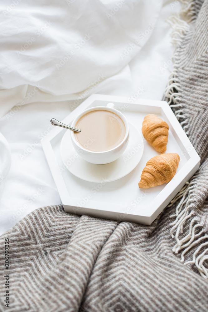 Cozy breakfast in bed, cup of coffee and croissants on white and
