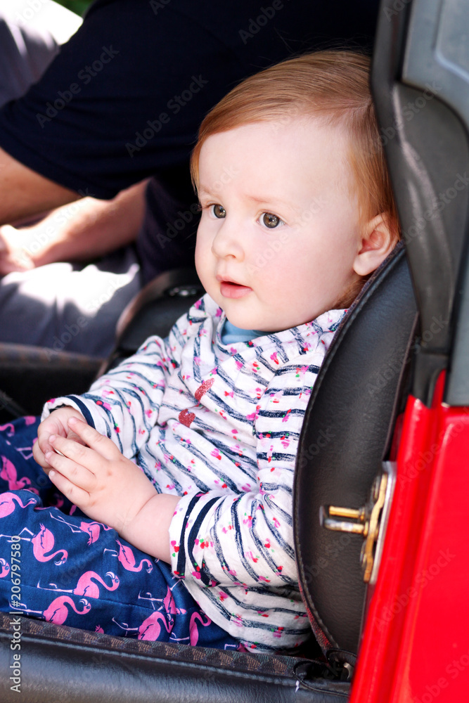 Baby sit in safety car seat. Cute little girl in car seats in car. Portrait of pretty toddler girl sitting in car seat. Child transportation safety. Little happy baby sitting on chair and looking. Baby sit in safety car seat. Cute little girl in car seats in car. Portrait of pretty toddler girl sitting in car seat. Child transportation safety. Little happy baby sitting on chair and looking.