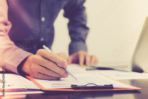 Businessman pen pointing graph chart for analyzing investment and calculate about profit and lost in his office.