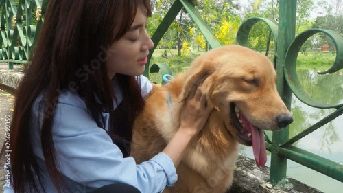 Young asian beautiful girl playing with her little golden retriever dog in park