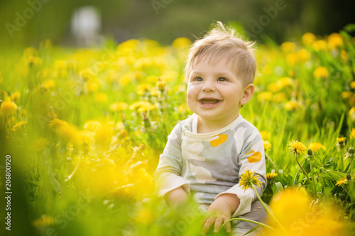 Concept: family values. Portrait of adorable innocent brown-eyed baby playing outdoor in the sunny dandelions field and making funny faces. © Mrakor