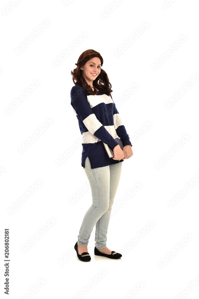 full length portrait of girl wearing striped blue and white jumper and jeans and holding a book. standing pose on white studio background full length portrait of girl wearing striped blue and white jumper and jeans and holding a book. standing pose on white studio background