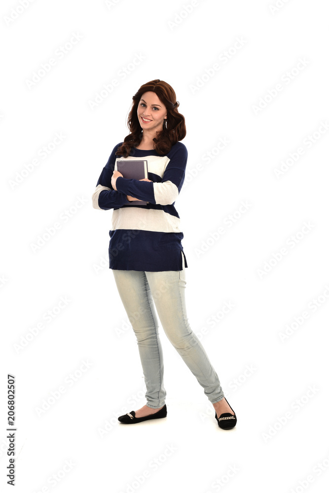 full length portrait of girl wearing striped blue and white jumper and jeans and holding a book. standing pose on white studio background full length portrait of girl wearing striped blue and white jumper and jeans and holding a book. standing pose on white studio background