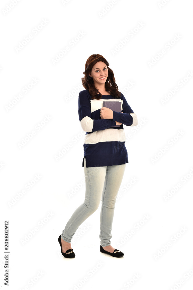 full length portrait of girl wearing striped blue and white jumper and jeans and holding a book. standing pose on white studio background full length portrait of girl wearing striped blue and white jumper and jeans and holding a book. standing pose on white studio background