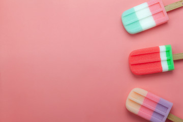 Table top view aerial image of food for summer holiday background concept.Flat lay arrangement variety ice cream pop stick on modern rustic pink paper wallpaper at office desk.Pastel tone design.