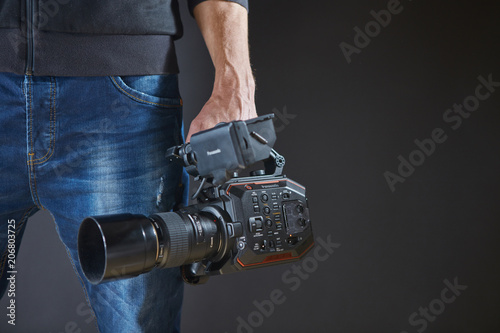 Kiev, Ukraine - April 22, 2018: Professional video man hand holding Video camera Panasonic AU-EVA1 operator camcorder in studio, photo