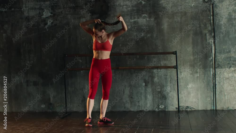 Beautiful woman comes in the fitness centre in the morning. Young girl is preparing for training indoor. Red sportswear. Beautiful woman comes in the fitness centre in the morning. Young girl is preparing for training indoor. Red sportswear.
