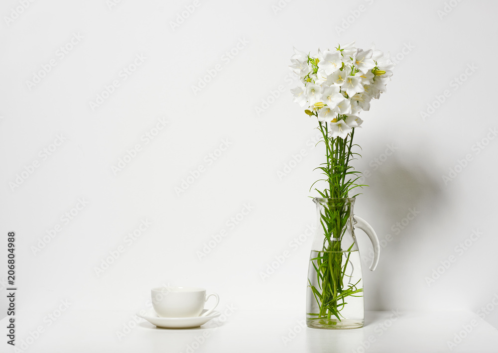 bellflower and a cup in a vase on a table by the wall, white background bellflower and a cup in a vase on a table by the wall, white background