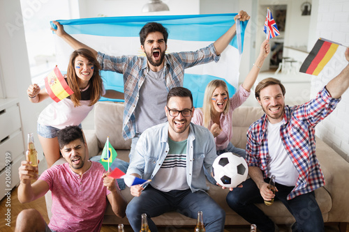 Cheerful group of friends watching football game on tv. © NDABCREATIVITY