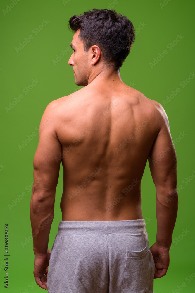 Fototapeta premium Young handsome Hispanic man shirtless against green background