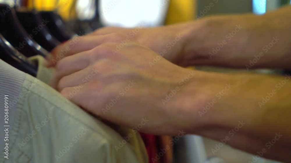 Male hands choosing jacket in the clothing store Close-up with changing focus Male hands choosing jacket in the clothing store Close-up with changing focus