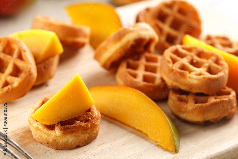 circle mini waffles with mango on wooden cutting board circle mini waffles with mango on wooden cutting board