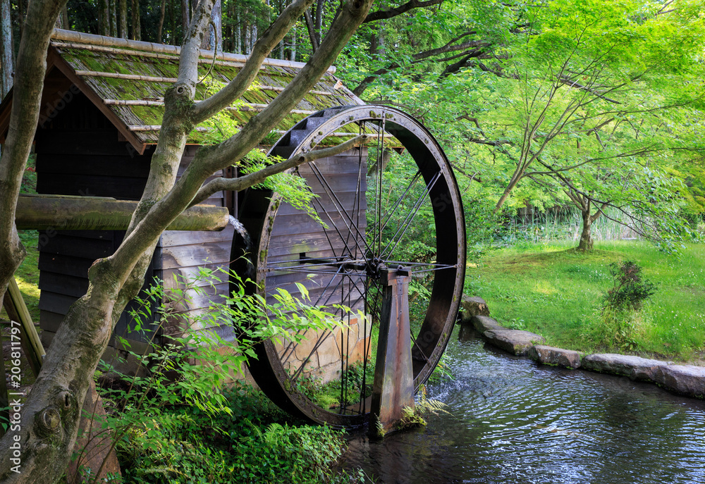 Old fashioned wooden waterwheel among green trees