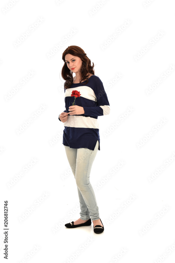full length portrait of girl wearing striped blue and white jumper and jeans, holding a red flower. standing pose on white studio background full length portrait of girl wearing striped blue and white jumper and jeans, holding a red flower. standing pose on white studio background