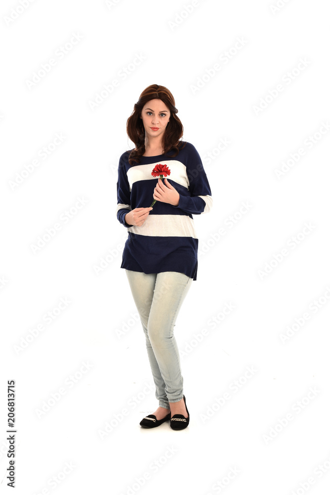 full length portrait of girl wearing striped blue and white jumper and jeans, holding a red flower. standing pose on white studio background full length portrait of girl wearing striped blue and white jumper and jeans, holding a red flower. standing pose on white studio background