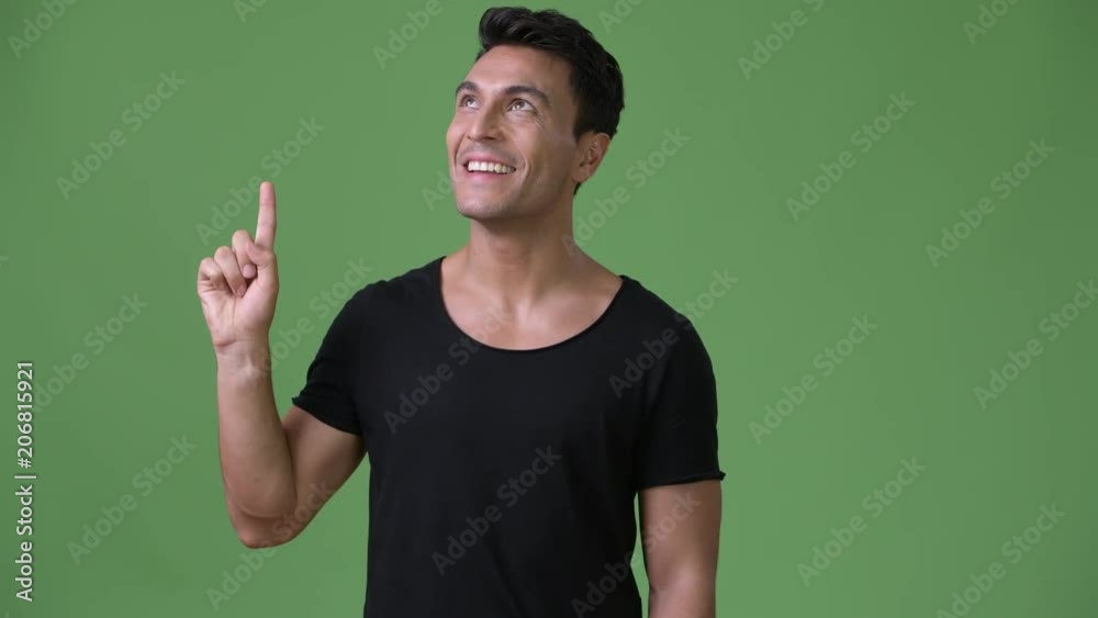 Young handsome Hispanic man against green background Young handsome Hispanic man against green background