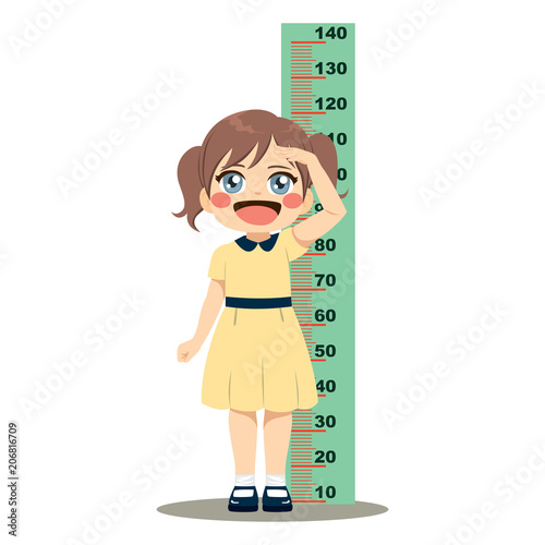 Cute little girl measuring her height with wall ruler