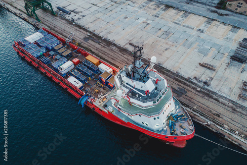 Container ship in export and import business and logistics. Shipping cargo to harbor by crane. Aerial view