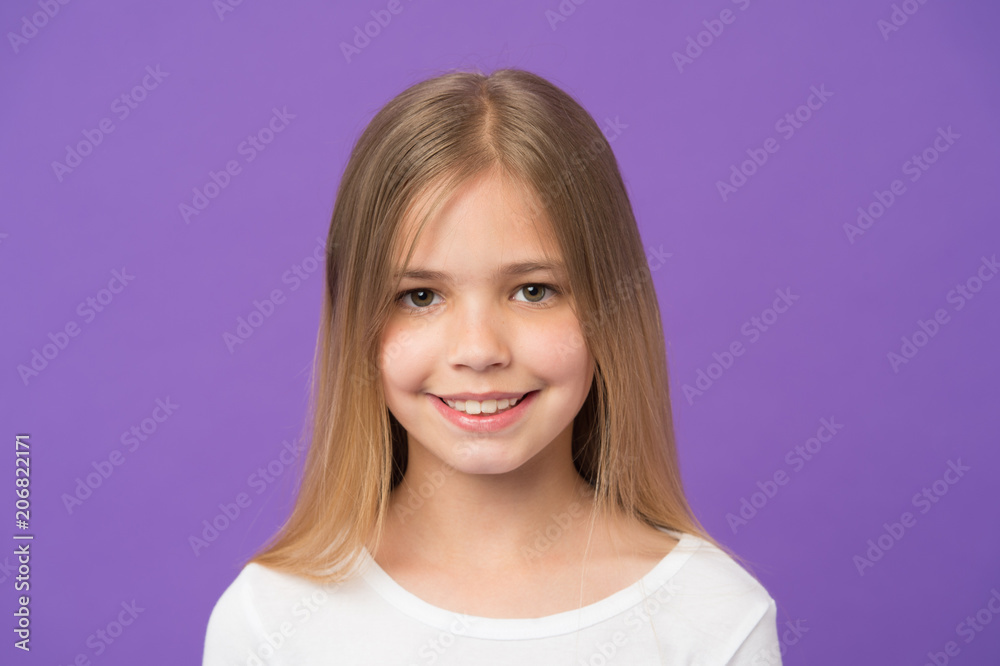 Beauty look and skincare. Little girl smile on violet background. Child with fresh skin on cute face. Beauty kid with happy look and long blond hair on purple background. Childhood and childcare Beauty look and skincare. Little girl smile on violet background. Child with fresh skin on cute face. Beauty kid with happy look and long blond hair on purple background. Childhood and childcare