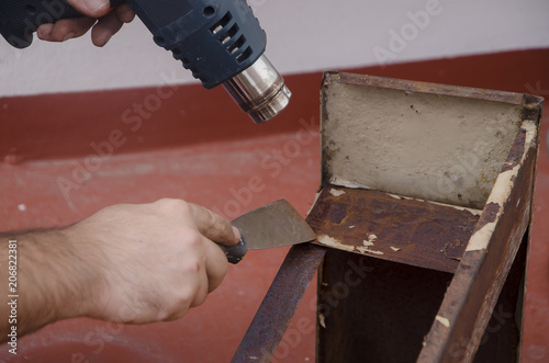 Manos de hombre caucásico utilizando una maquina decapadora de pintura. Pistola de calor. photo