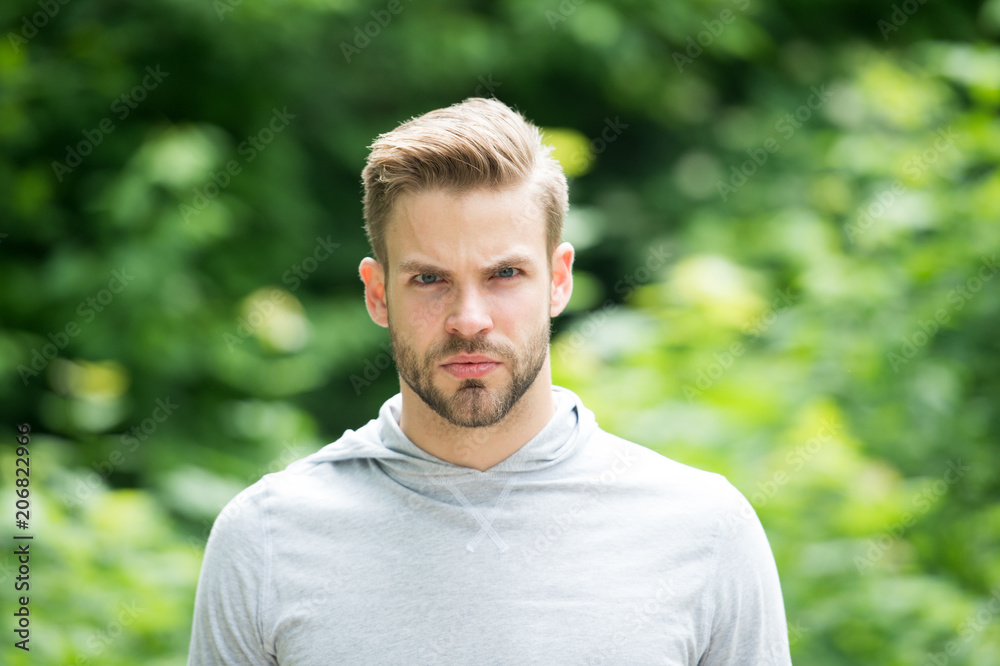 Guy bearded and attractive cares about appearance. Man with bristle on serious face, green nature background, defocused. Metrosexual concept. Man with beard or unshaven guy looks handsome and cool Guy bearded and attractive cares about appearance. Man with bristle on serious face, green nature background, defocused. Metrosexual concept. Man with beard or unshaven guy looks handsome and cool