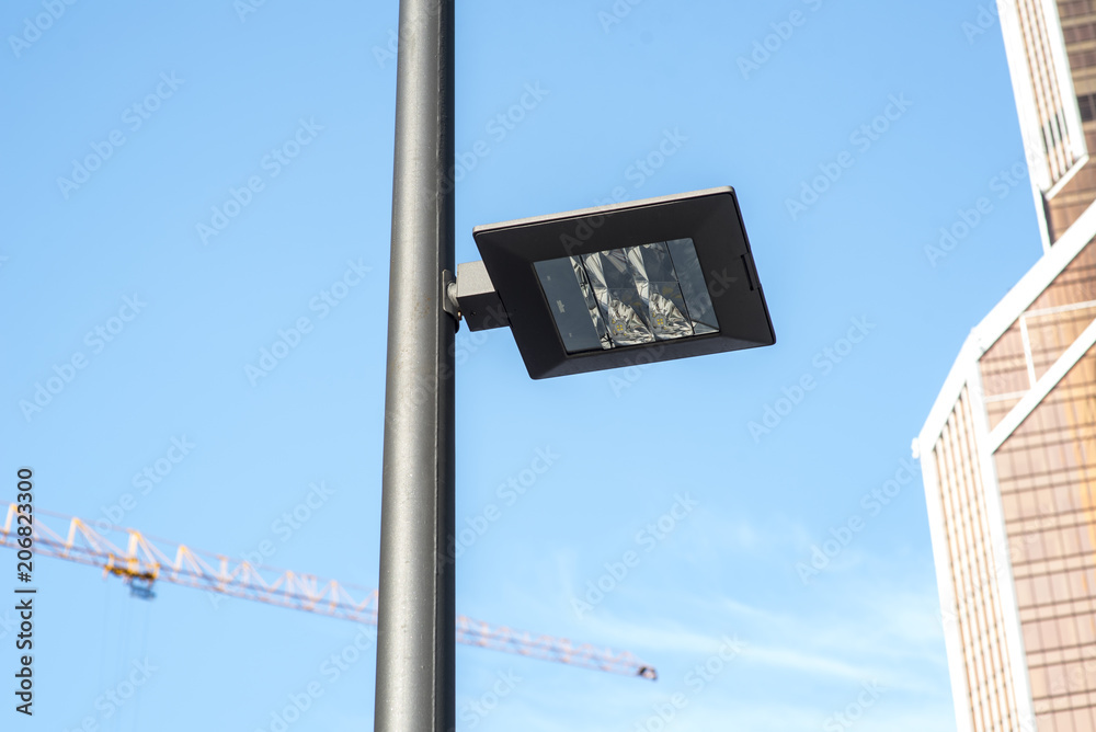 Modern street lights illuminated at day light against glass and steel office buildings