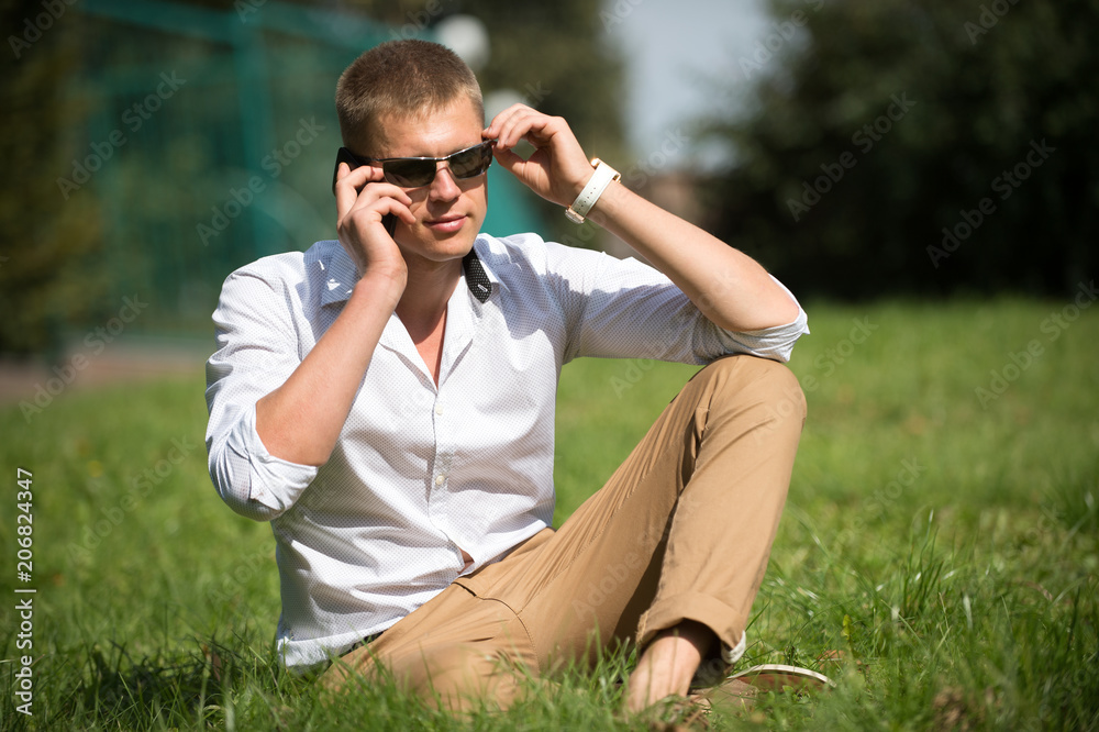 Handsome macho enjoy summer day. Businessman in sunglasses on sunny outdoor. Man relax on green grass. Fashion style and trend. Break time concept