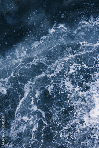 Surface of the sea with waves, splash, foam and bubbles at high tide and surf, blue abstract background