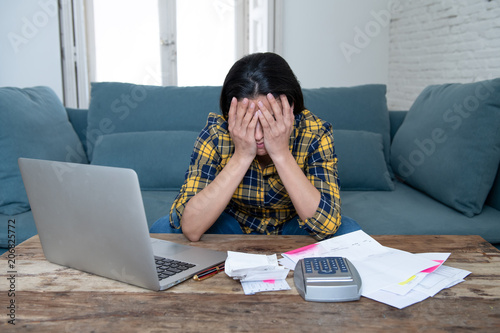 Attractive stressed woman managing finances, reviewing bank accounts, paying bills using laptop