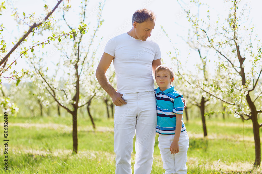 Father and son embrace in the garden in the spring of summer. Father's Day. Father and son embrace in the garden in the spring of summer. Father's Day.