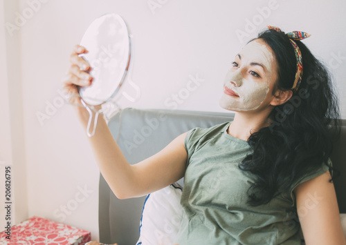 Girl with a clay face mask. Girl making clay mask for face, a beauty treatment in their room. 
