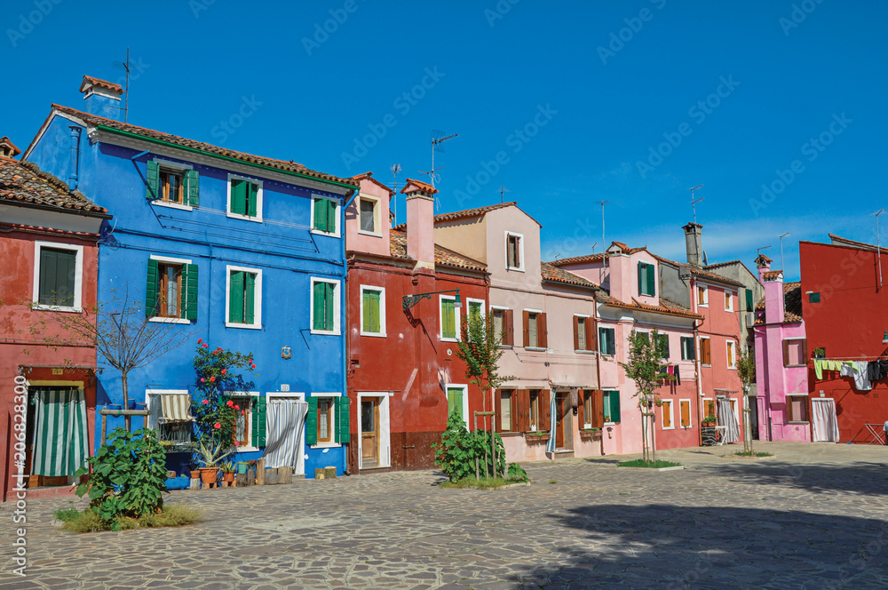 Overview of colorful terraced houses on sunny day in Burano, a gracious little town full of canals, near Venice. Located in the Veneto region, northern Italy